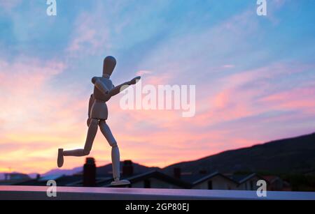 Wooden figure mannequin running at sunset Stock Photo