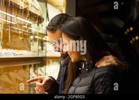 Happy beautiful young couple choosing a wedding rings while smiling while doing shopping in Florence. Stock Photo