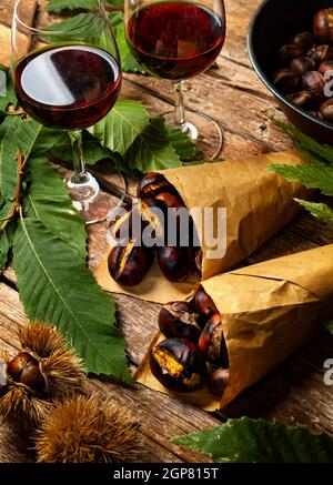 Roasted chestnuts in paper cones on wooden table. Stock Photo