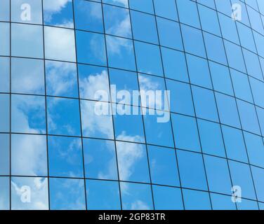 Modern glass skycrapers background with sky and clouds reflection. Stock Photo