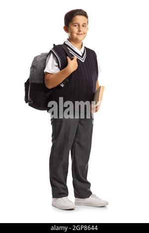 Full length portrait of a male pupil in a school uniform holding a book and carrying a backpack isolated on white background Stock Photo