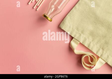 Fabric cotton shopping bags, glass bottles and jars, paper straws and wooden sticks on a pink background. Zero waste and ecological concept. Top view. Stock Photo