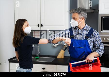 Woman Elbow Bump With Repair Man Or Handyman In Face Mask