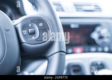 Close up of a steering wheel with remote control, blurry dashboard Stock Photo