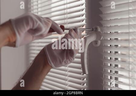 Close-up of hands in gloves with screwdriver, installing a new handle. Stock Photo