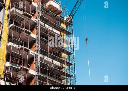 A horizontal shot of a tall building being built on a sunny day with a crane next to it Stock Photo