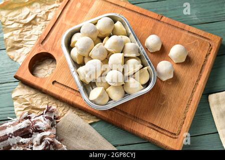 Frozen homemade raw food of ravioli on wooden board table, cooking process semi finished pelmeni dumplings. Stock Photo