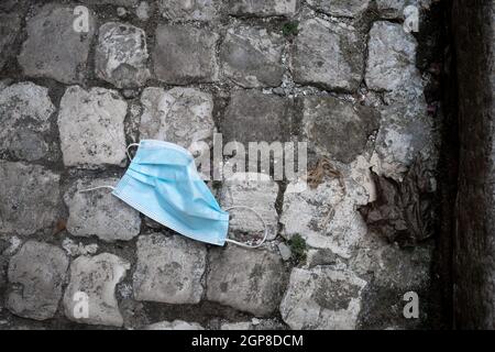 Horizontal picture. Used blue medical mast FFTP-2 frown away on grey cobblestone pavement. Black and white with blue. Contrast picture. Pollution Stock Photo