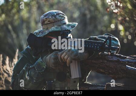 Airsoft military game player in camouflage uniform with armed assault rifle. Stock Photo