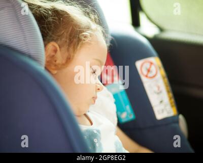 Cute blond baby sleeping in baby car seat. Safety Concept. Stock Photo