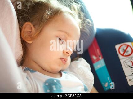 Cute blond baby sleeping in baby car seat. Safety Concept. Stock Photo