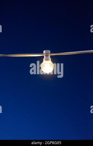 Yellow light bulbs on the background of the evening blue sky. Stock Photo