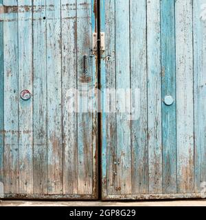 fragment of very old wooden door with blue cracked paint, parallel boards, full frame Stock Photo