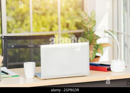 Back laptop computer putting on working desk, Workplace with notebook laptop on the table, Home interior or office background Stock Photo