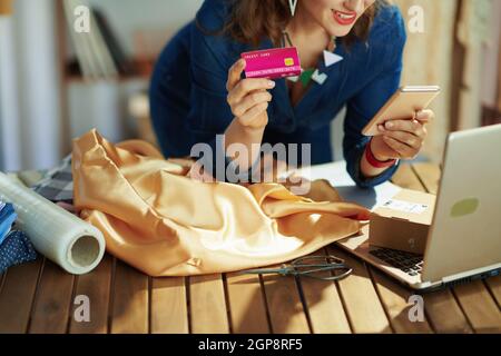 Closeup on small business owner woman with credit card using smartphone in the office. Stock Photo