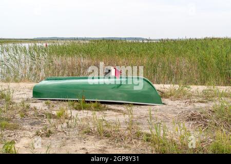 Fishing boat on the beach by the lake turned upside down Stock Photo