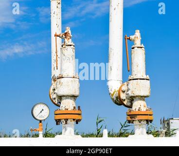 Steel spring safety valve and pressure gauge on the pressure vessel. Oil field equipment Stock Photo