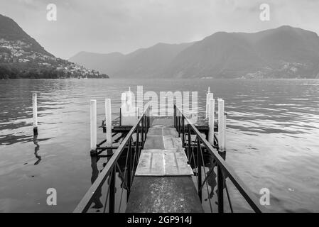 Boat pier on the Lake Lugano, Switzerland. Black and white photography. European vacation, travel and nautical concept. Stock Photo