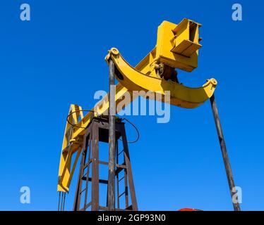The pumping unit as the oil pump installed on a well. Equipment of oil fields. Stock Photo