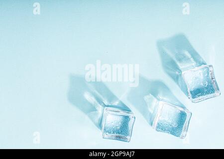 Ice cubes on vibrant light blue colors. Concept art. Minimal surrealism. Flat lay with copy space. Soft focus. Stock Photo