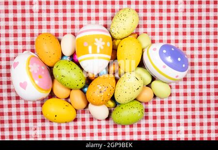 Mix of easter eggs of all colors and sizes on a background of red and white gingham fabric. Easter concept. Stock Photo