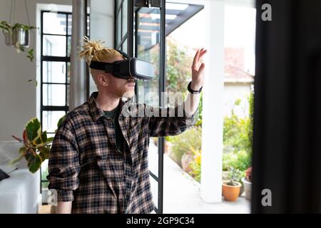 Albino african american man with dreadlocks working from home and using vr headsets Stock Photo
