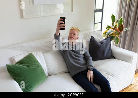 Albino african american man in the living room taking selfie Stock Photo