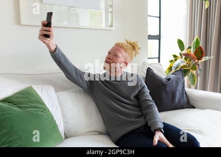 Albino african american man in the living room taking selfie Stock Photo
