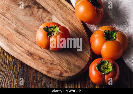 Four Ripe and Sweet Persimmons on Cutting Board Stock Photo