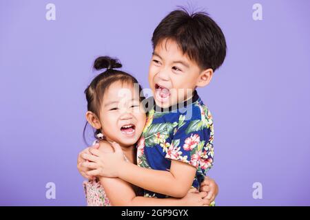 Asian Two happy funny little cute kids stand together in studio shot isolated on purple background, happy family brother and sister hugging each other Stock Photo