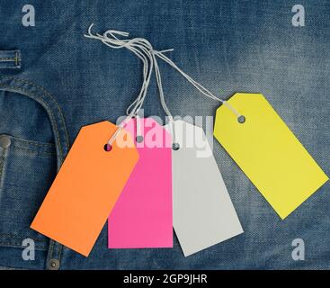 blank rectangular cardboard colored tags on blue jeans background, top view Stock Photo