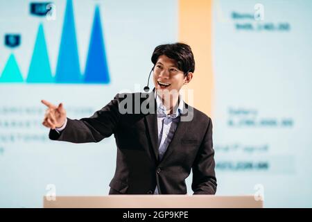 Asian Businessman Stands on Stage for Business Presentation Stock Photo