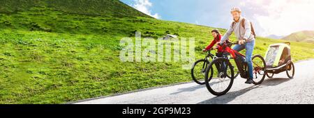 Family Riding Electric Mountain Bike Or Bicycle In Mountains Stock Photo