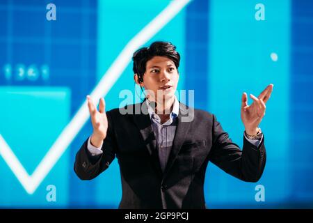 Asian Businessman Stands on Stage for Business Presentation Stock Photo