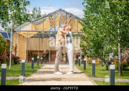 Man hugging his smiling female spouse outdoors Stock Photo