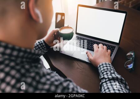 Man working at laptop with cup of coffee, headphones at home. Blurred background. High quality photo Stock Photo