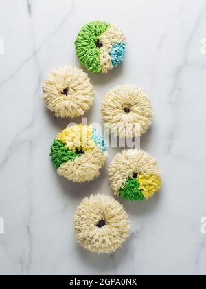 Shag donuts on white marble background. Unusual trendy colorful donuts with vanilla buttercream. Copy space. Top view or flat lay. Vertical Stock Photo