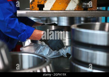 Packaging of finished bearings for production. Storage of finished products in a bearing manufacturing plant. The concept of hard physical labor. Unre Stock Photo
