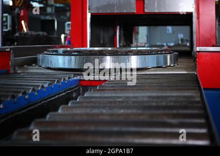 The finished large diameter bearing is coated with oil before packaging and storage. Metal products. Conveyor in the production of bearings.Heavy indu Stock Photo