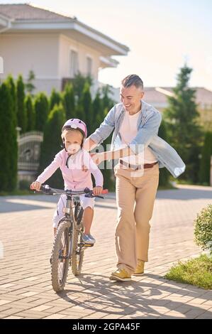 Little girl learning to ride bike with father Stock Photo