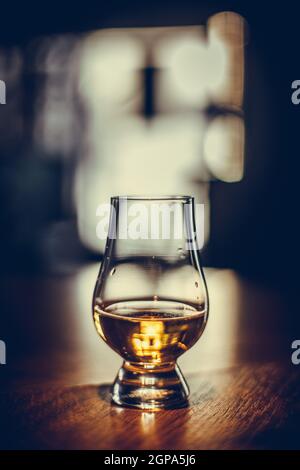 Color close up shot of a Glencairn whisky glass on a wooden table, with shallow depth of field. Stock Photo