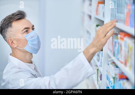 Male pharmacist looking for medicine on shelf Stock Photo