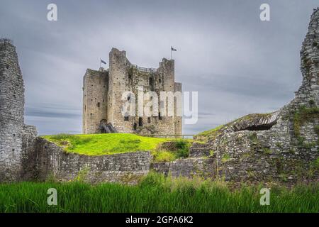 View on Trim Castle through a gap between fortification walls with dark moody sky in Trim village, County Meath, Ireland Stock Photo