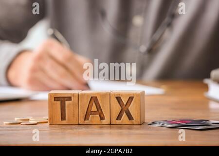 Word TAX with coins and credit cards on table Stock Photo