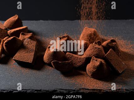 The moment you sprinkle cocoa powder on the truffle chocolate placed on the stone plate Stock Photo