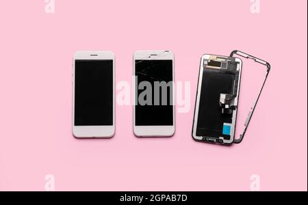 Broken and new mobile phones and display module on pink background Stock Photo