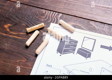 Furniture assembling plan and dowels on wooden background, closeup Stock Photo