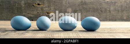 Naturally colored organic eggs in a row on a rustic table with space for text, Easter background Stock Photo