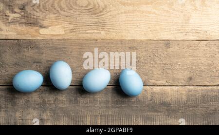 Naturally colored organic eggs in a row on a rustic table with space for text, Easter background Stock Photo