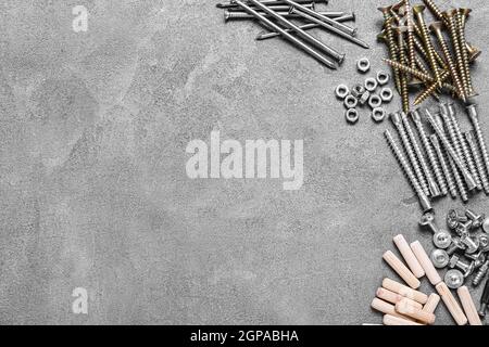 Different nuts, bolts, screws, nails and dowels on grey background Stock Photo